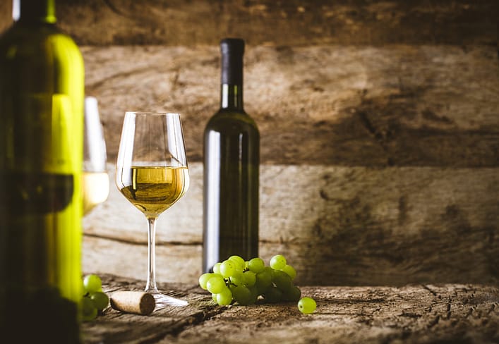 Wine. Glass of white wine in wine cellar. Old white wine on wood.